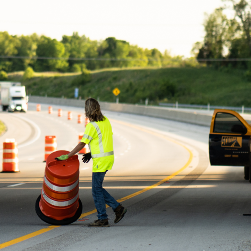 construction worker rolling a construction cone